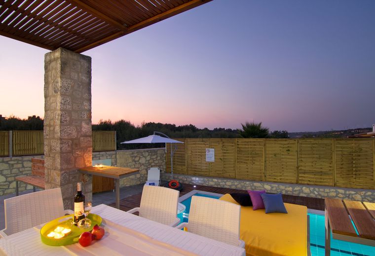 Laid table on the covered terrace of Villa Aada at dusk