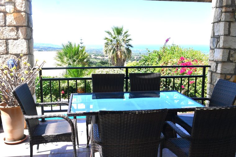 Villa Mailin terrace with a laid table and a view over palms to the coast